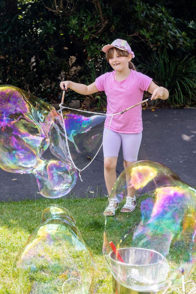 Girl playing with Giant bubbles in Morrab Gardens, Penzance.